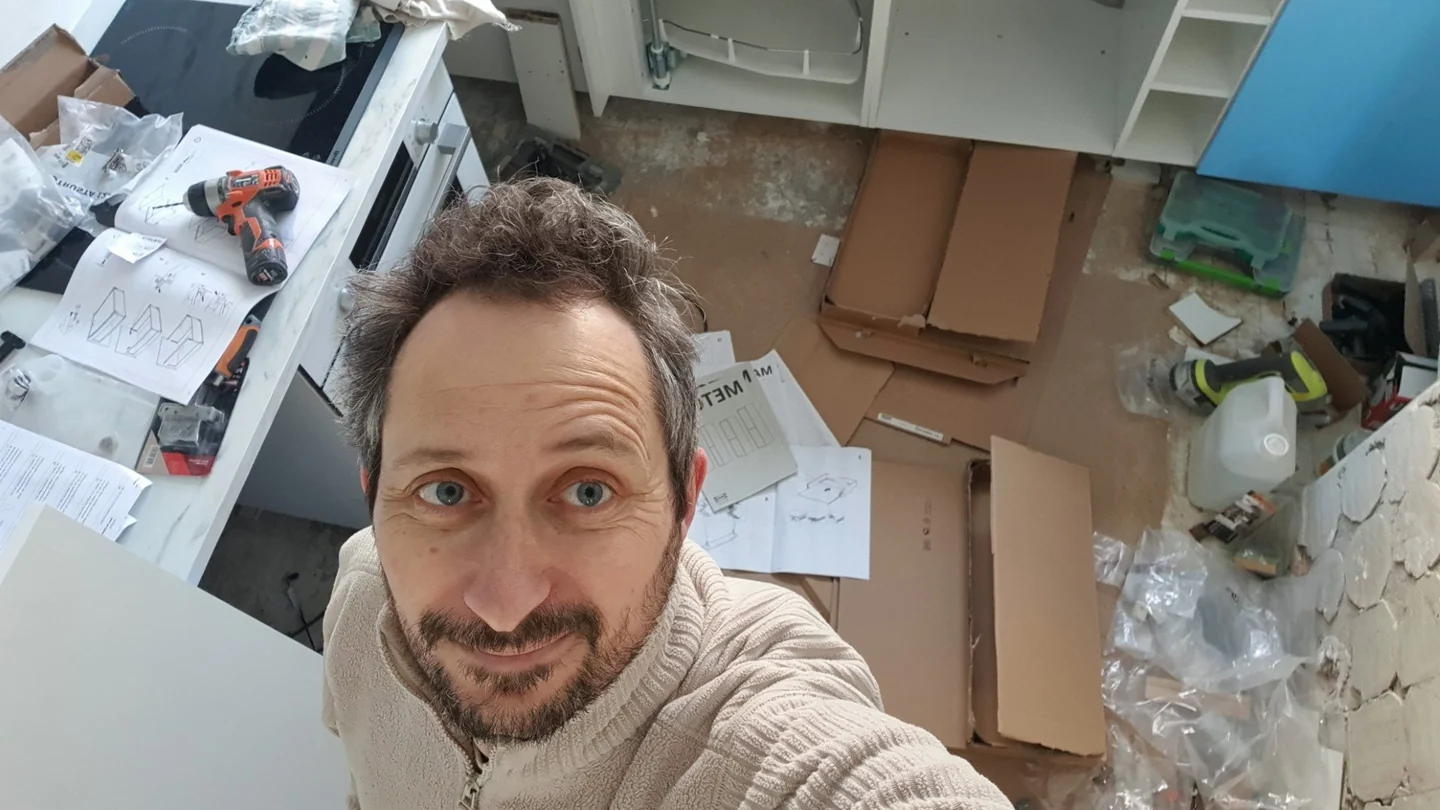 Guillaume dans un appartement en cours de rénovation, avec les outils et les notices de montage.