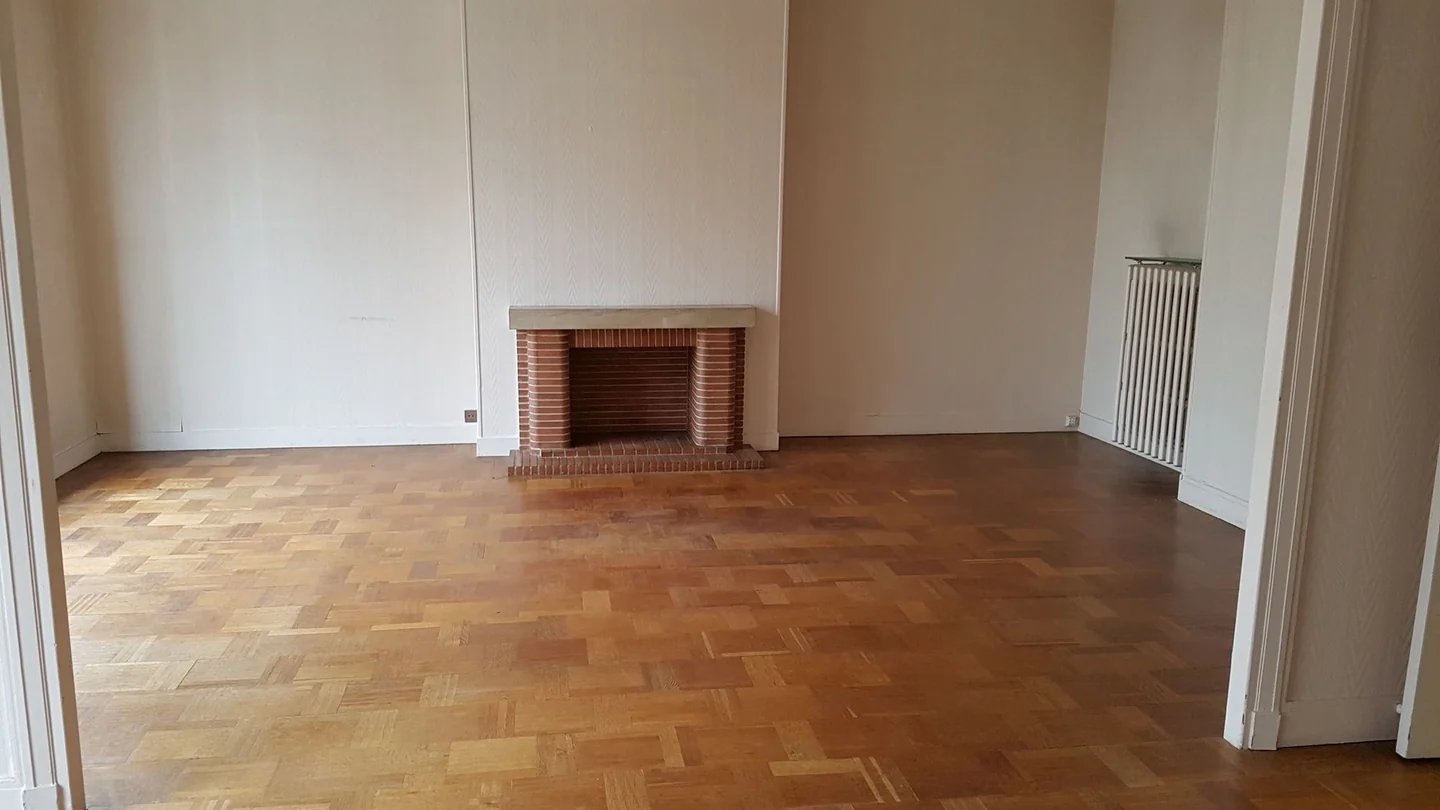 Salon avant rénovation, avec une cheminée en briques et un parquet.